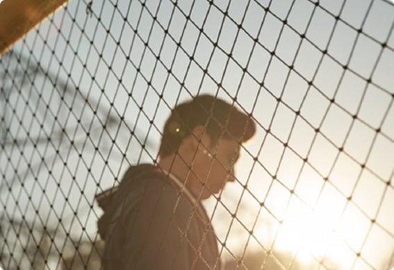 a baseball player behind a chain link fence