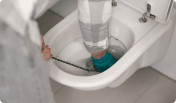 a person snaking a toilet