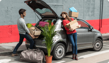 a man and woman loading things into a car's trunk