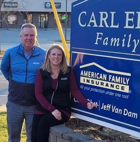 a man and woman posing for a picture next to a sign