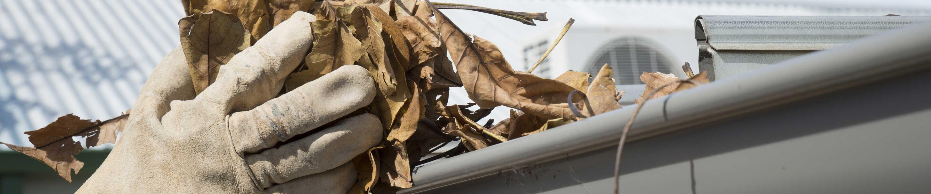 Man cleaning gutters to prepare for spring storms.