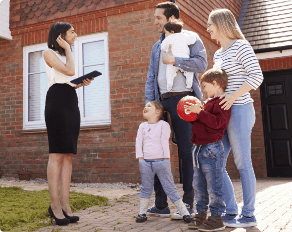 A realtor speaking to a family in front of a duplex.