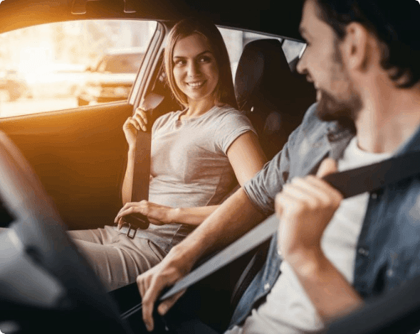 Happy couple sitting in their car and putting their seatbelts on.