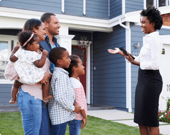 A family and realtor talking in front of a new home.