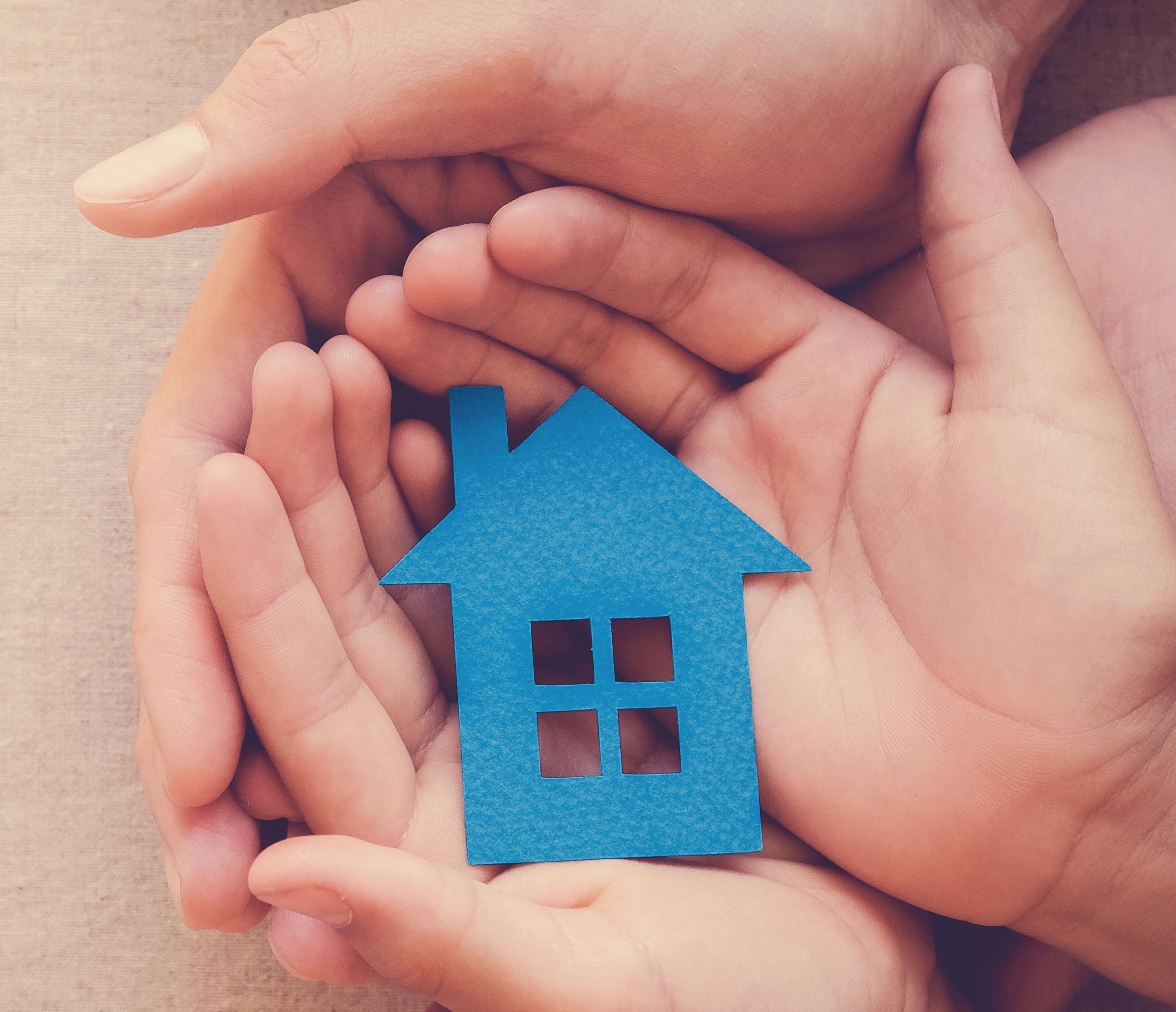 Child holding a paper cut out of a house