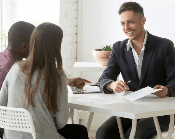 Image of a young couple reviewing their life insurance policies with their insurance agent.