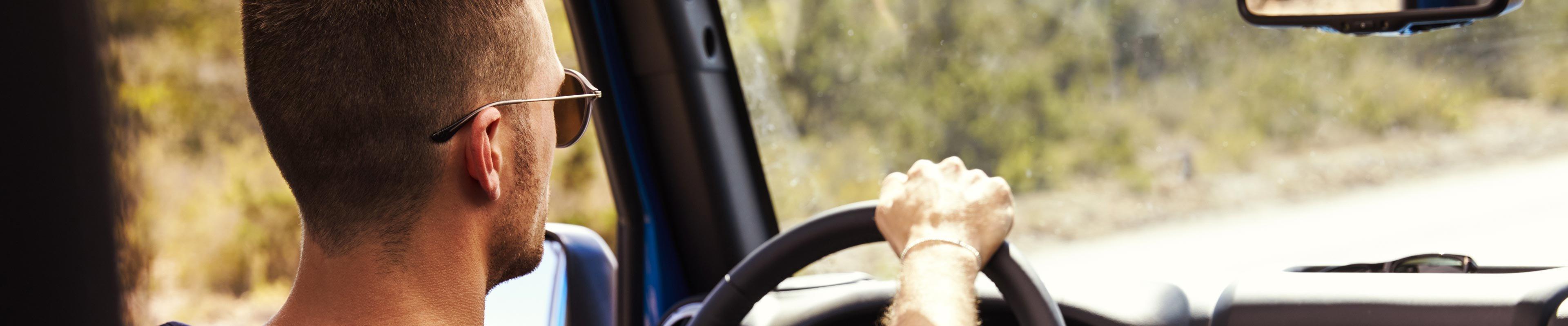 Man wearing sunglasses driving his car down the road