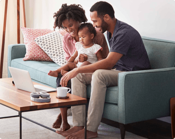 parents on the couch with their baby looking at a computer