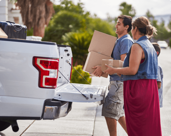 Family moving boxes out of a pick up truck