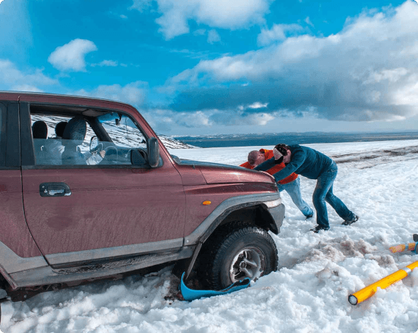 people pushing a truck stuck in snow