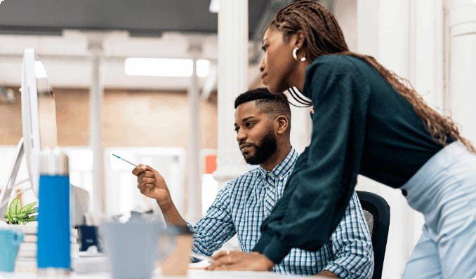 Two professionals looking at a computer screen while talking.